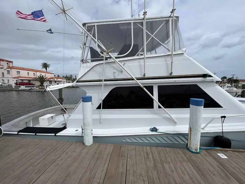 Slide: The Image of 1991 Viking Convertible yacht docked at marina with American flag, overcast sky. - 4