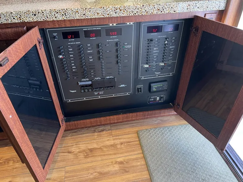 Slide: The Image of Electrical panel inside a 1991 Viking Convertible boat with open wooden cabinet doors. - 44