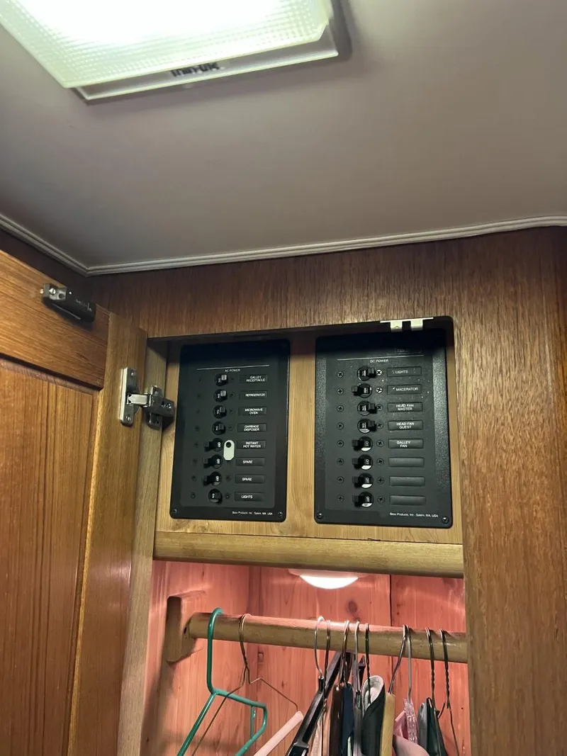 Slide: The Image of Electrical panel inside a 1991 Viking Convertible boat, wooden cabinet, clothes hanging below. - 53