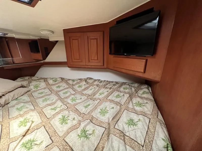 Slide: The Image of Cozy bedroom in 1991 Viking Convertible boat with TV and patterned bedding. - 59
