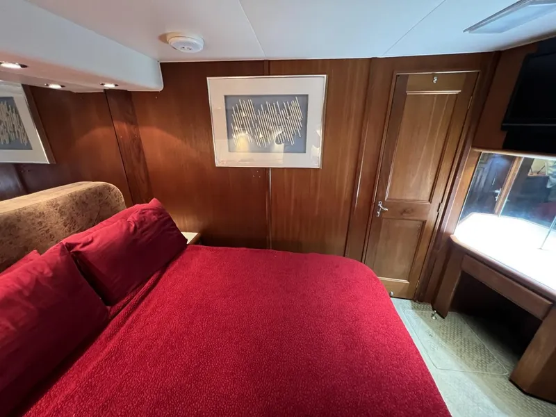 Slide: The Image of Luxurious bedroom in 1991 Viking Convertible yacht with red bedding and wooden paneling. - 64