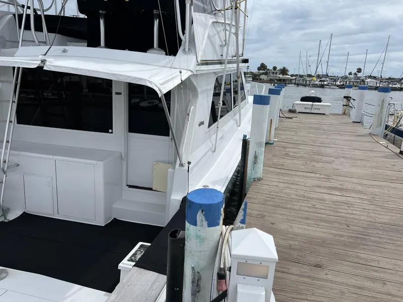 Slide: The Image of 1991 Viking Convertible yacht docked at a marina with wooden pier and sailboats in the background. - 7