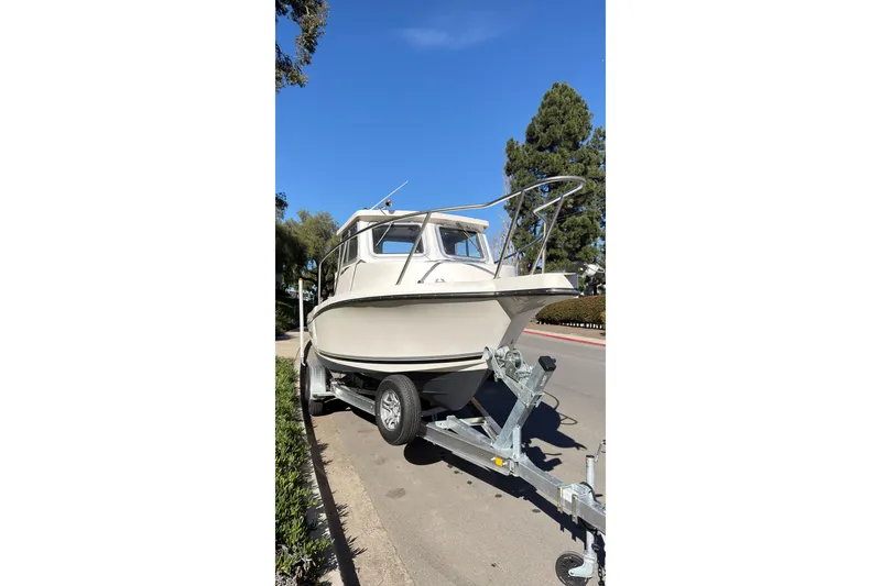 Slide: The Image of 2026 Defiance Admiral 220 EX boat on trailer, parked on a sunny street. - 4