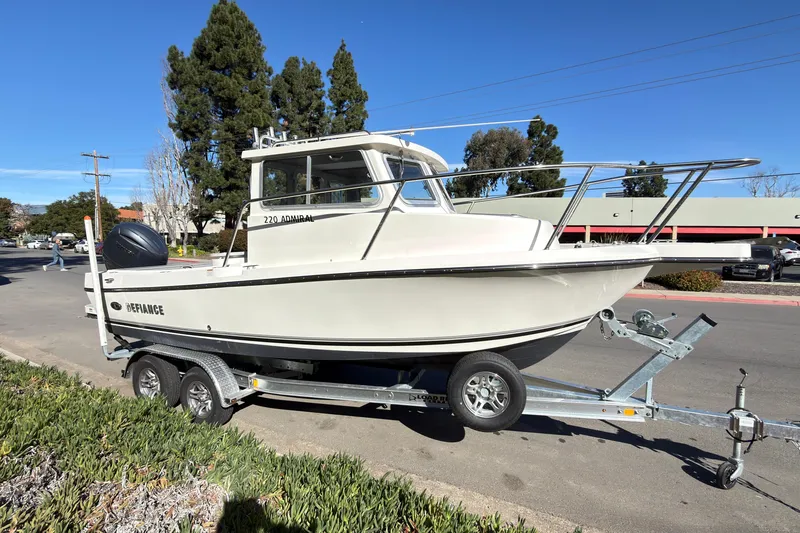 Slide: The Image of 2026 Defiance Admiral 220 EX boat on trailer, parked on street, clear sky background. - 6