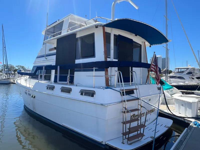 The Image of 1986 Gulfstar 44 Aft Cabin yacht docked in marina, featuring blue accents and American flag. - 0