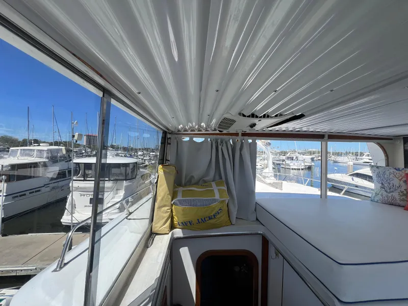 Slide: The Image of 1986 Gulfstar 44 Aft Cabin interior view with marina backdrop, featuring seating and life jacket. - 30