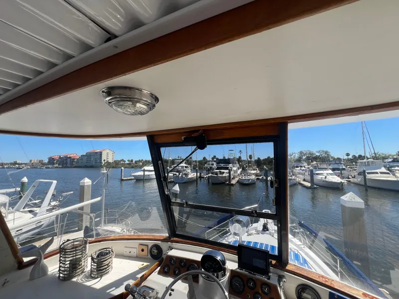 Slide: The Image of 1986 Gulfstar 44 Aft Cabin yacht helm with marina view, featuring navigation equipment and clear skies. - 32