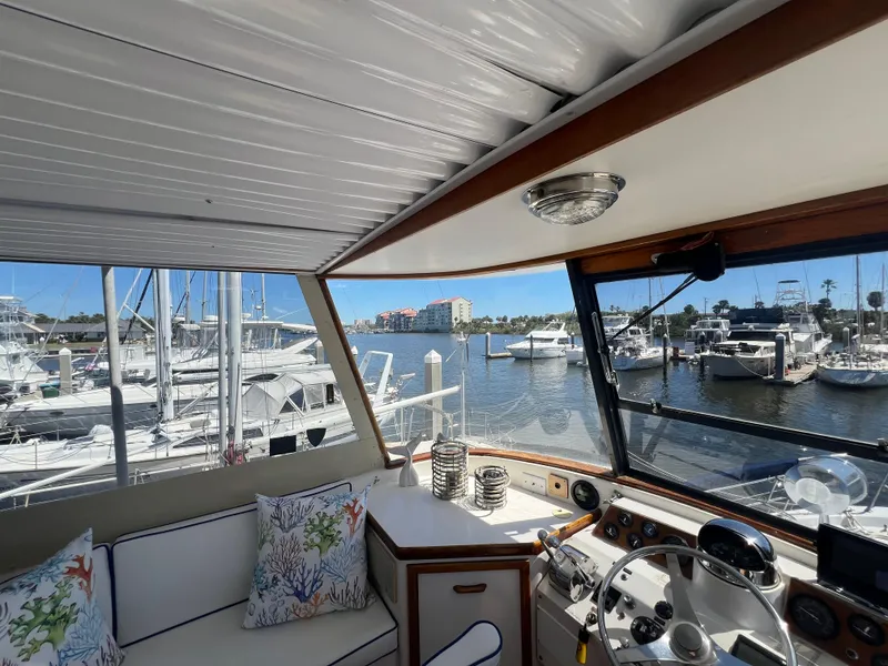 Slide: The Image of 1986 Gulfstar 44 Aft Cabin yacht interior with marina view, featuring helm and seating area. - 33