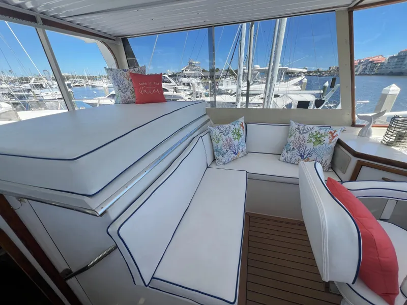 Slide: The Image of 1986 Gulfstar 44 Aft Cabin interior with white seating, colorful cushions, and marina view. - 43