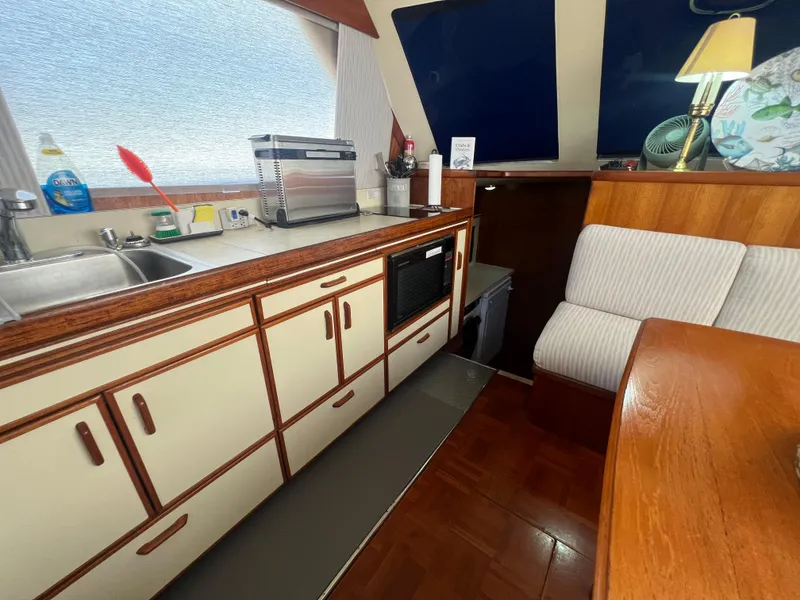 Slide: The Image of 1986 Gulfstar 44 Aft Cabin interior with kitchen, seating, and wooden cabinetry. - 49