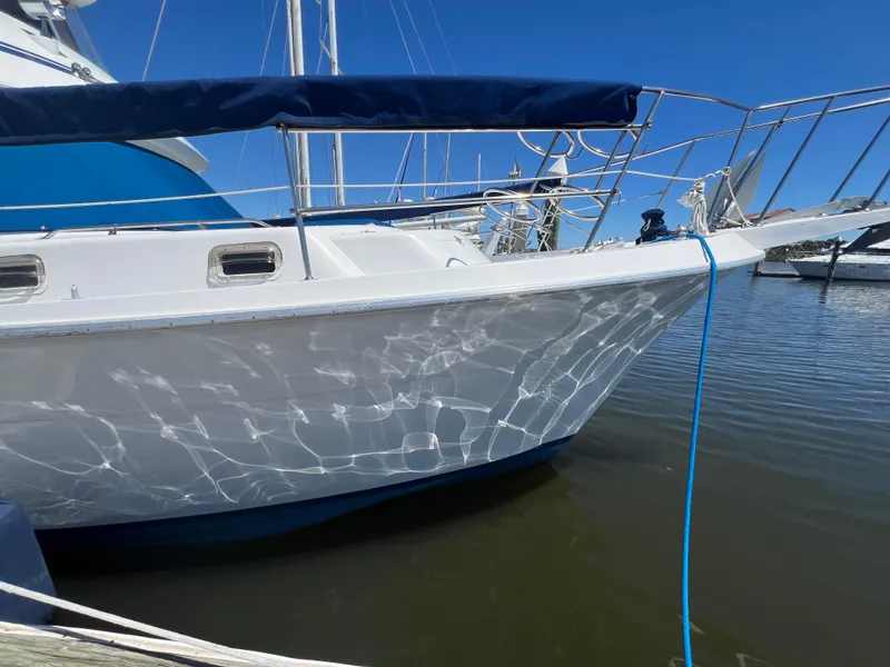 Slide: The Image of 1986 Gulfstar 44 Aft Cabin yacht docked, reflecting sunlight on calm water. - 9