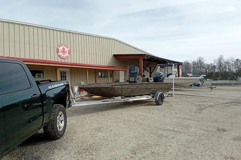 Slide: The Image of 2026 Alweld 2070 Vortex boat on trailer outside a warehouse, hitched to a truck. - 4