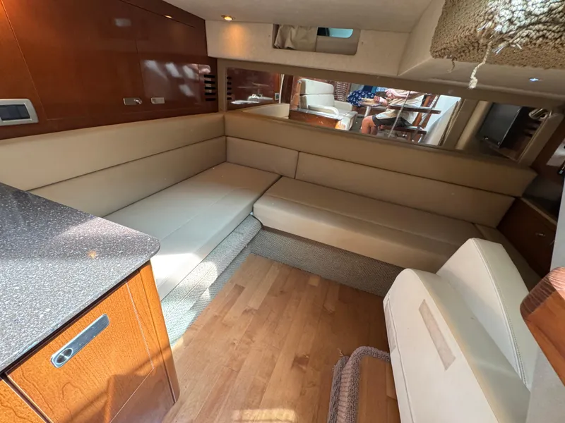 Slide: The Image of Interior of 2012 Sea Ray 370 Sundancer with beige seating and wooden cabinetry. - 10