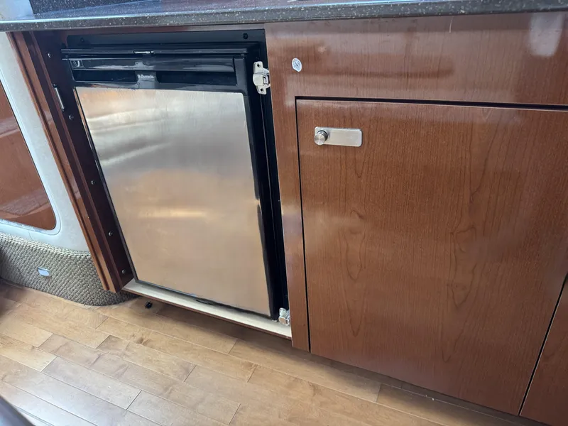 Slide: The Image of Interior of 2012 Sea Ray 370 Sundancer with stainless steel fridge and wooden cabinetry. - 12