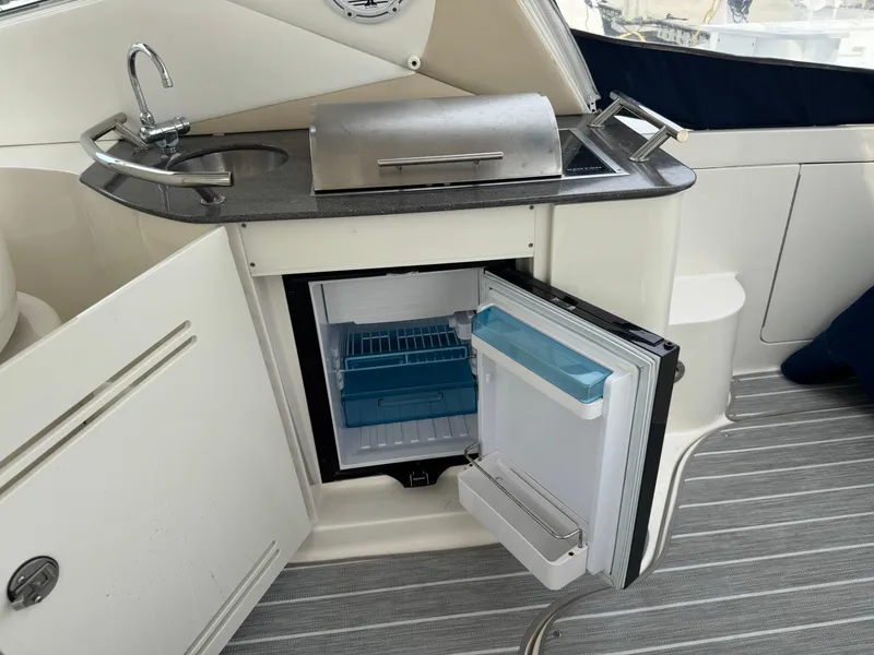 Slide: The Image of 2012 Sea Ray 370 Sundancer kitchenette with sink, grill, and open mini fridge. - 22