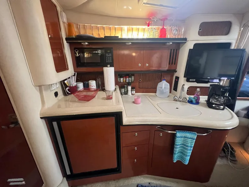 Slide: The Image of 2002 Sea Ray 340 Sundancer kitchen with microwave, sink, and TV. - 17