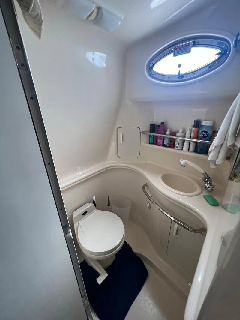 Slide: The Image of 2002 Sea Ray 340 Sundancer bathroom with toilet, sink, and oval window. - 18