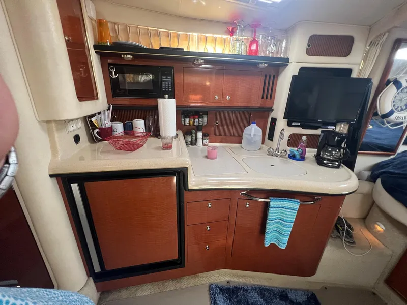 Slide: The Image of 2002 Sea Ray 340 Sundancer galley with wood cabinetry, microwave, and TV. - 19