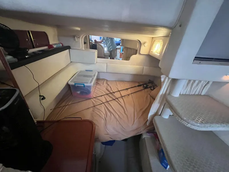 Slide: The Image of 2002 Sea Ray 340 Sundancer cabin interior with bed, fishing rods, and storage. - 23