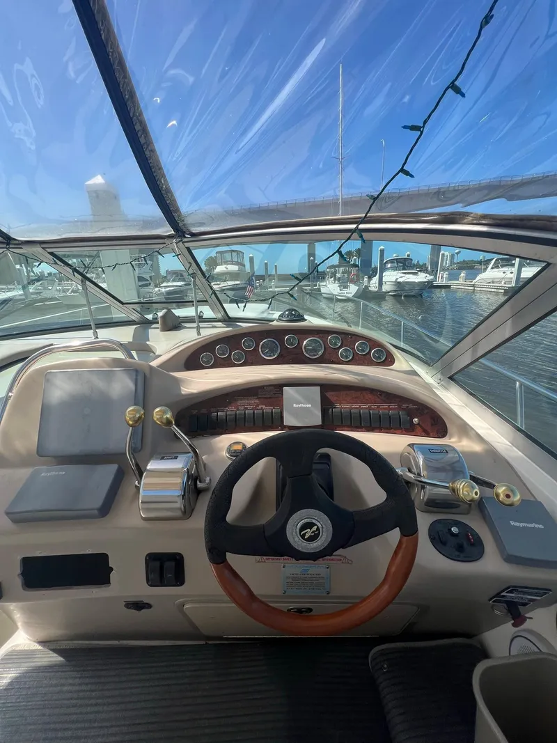 Slide: The Image of 2002 Sea Ray 340 Sundancer helm with gauges, steering wheel, and marina view. - 8