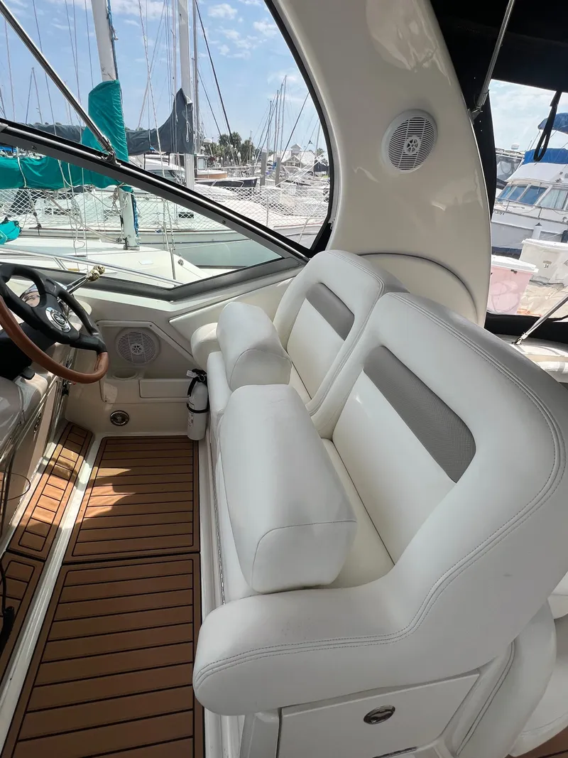 Slide: The Image of 2003 Sea Ray 320 Sundancer cockpit with white seating and wood flooring, docked at marina. - 12