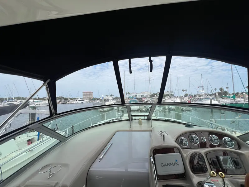 Slide: The Image of 2003 Sea Ray 320 Sundancer helm with Garmin navigation, docked at marina with boats in view. - 32