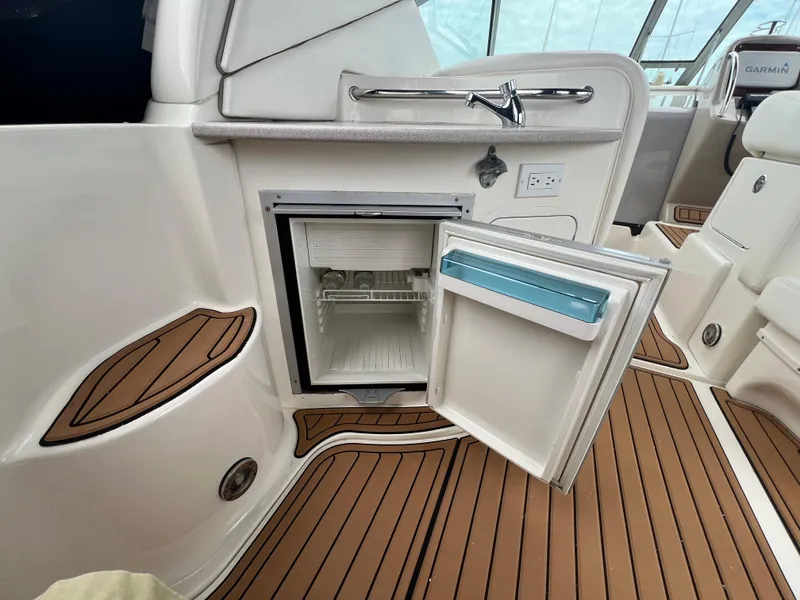 Slide: The Image of 2003 Sea Ray 320 Sundancer boat interior with open mini fridge and teak flooring. - 38