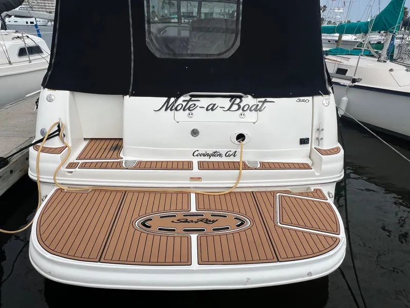 Slide: The Image of 2003 Sea Ray 320 Sundancer boat docked, featuring teak deck and black canopy. - 43
