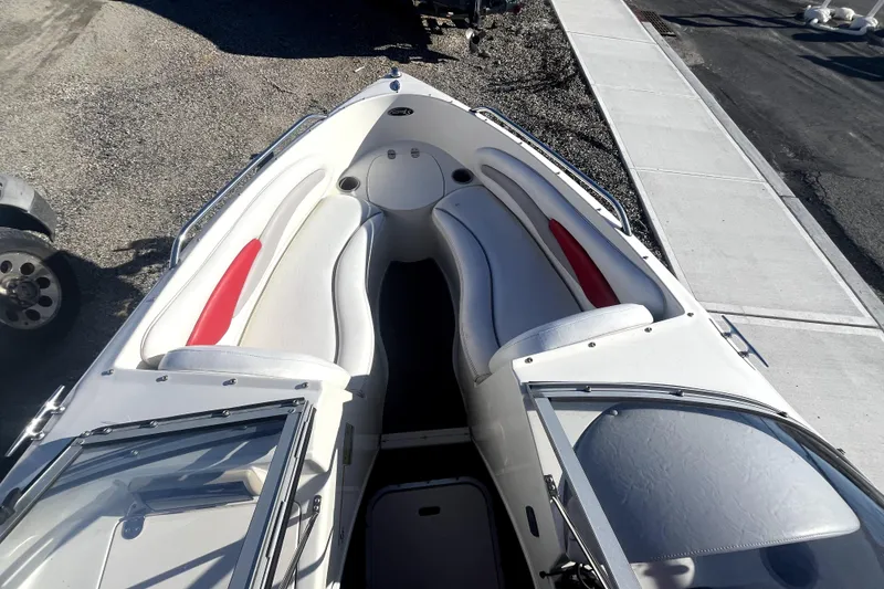Slide: The Image of 2007 Stingray 185 LS/LX boat interior with white and red seating, docked near a road. - 7