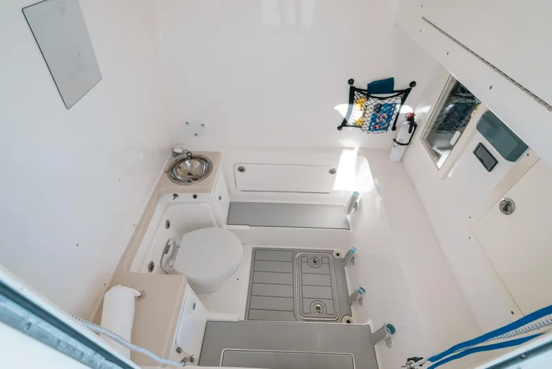 Slide: The Image of Interior of 2016 Invincible 42 Open Fisherman boat, featuring a compact bathroom with sink and toilet. - 33
