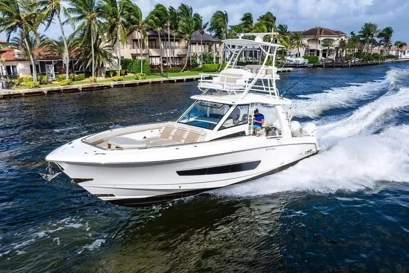 The Image of 2022 Boston Whaler 420 Outrage cruising on a scenic waterway with palm trees. - 0