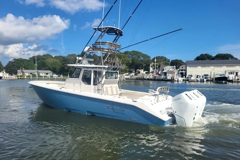 Slide: The Image of 2026 Solace 37 Pilot boat on water, blue hull, twin engines, sunny day. - 2
