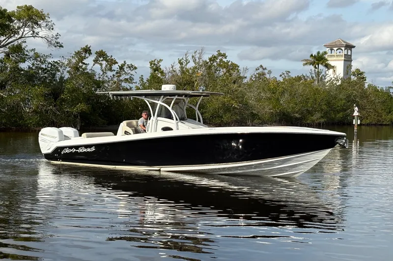 The Image of 2012 Nor-Tech 340 Sport Center Console boat cruising on calm water, surrounded by lush greenery. - 0