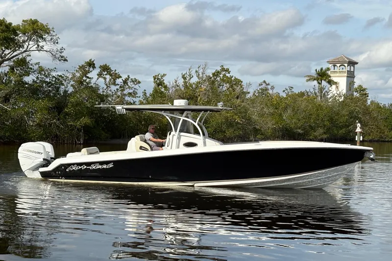 Slide: The Image of 2012 Nor-Tech 340 Sport Center Console boat cruising on calm water near lush greenery. - 2