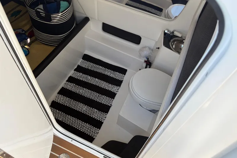Slide: The Image of Interior of 2012 Nor-Tech 340 Sport Center Console boat with toilet and striped rug. - 23