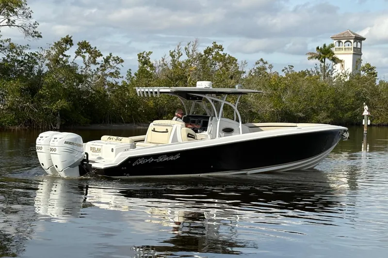Slide: The Image of 2012 Nor-Tech 340 Sport Center Console boat on calm water, surrounded by trees. - 4