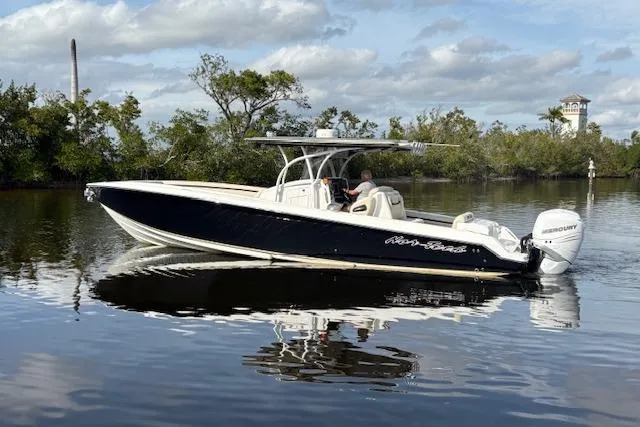 Slide: The Image of 2012 Nor-Tech 340 Sport Center Console boat on calm water, surrounded by trees. - 7