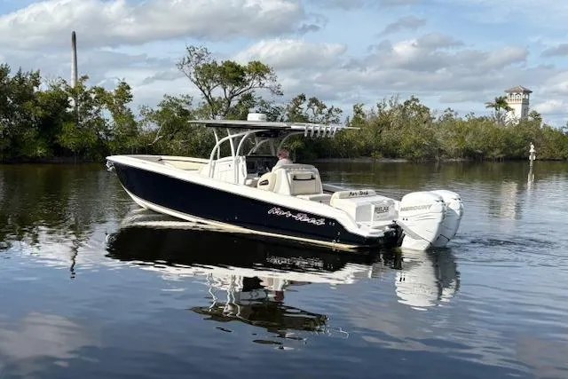 Slide: The Image of 2012 Nor-Tech 340 Sport Center Console boat on calm water, surrounded by trees. - 9
