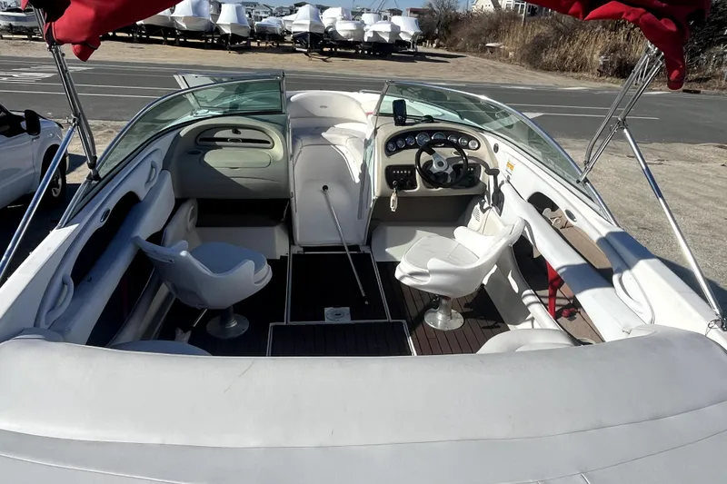 Slide: The Image of 2002 Chaparral 216 SSi boat interior with white seating and dashboard, parked outdoors. - 6