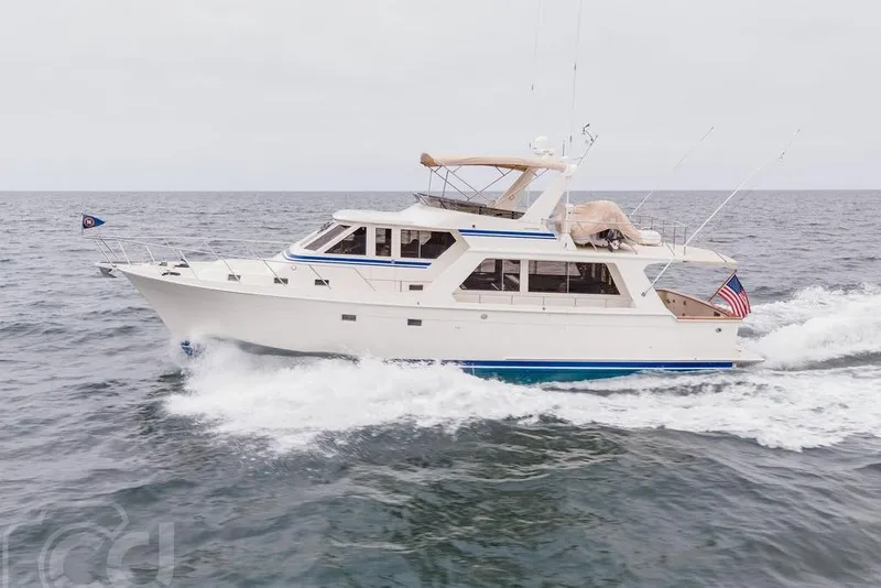 Slide: The Image of 1999 Offshore Yachts 52 Pilothouse cruising on open sea, displaying American flag. - 1