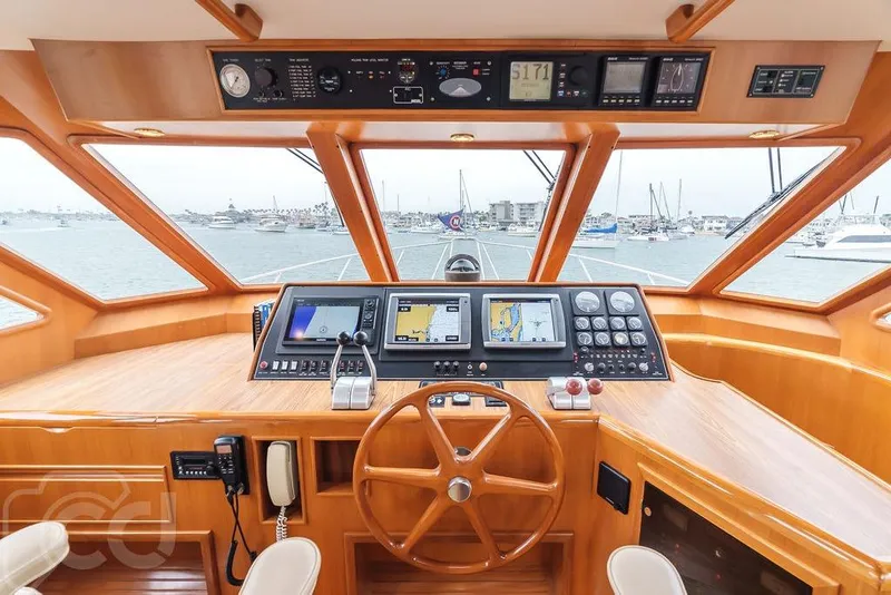 Slide: The Image of Pilothouse of 1999 Offshore Yachts 52, featuring navigation equipment and wooden steering wheel. - 14