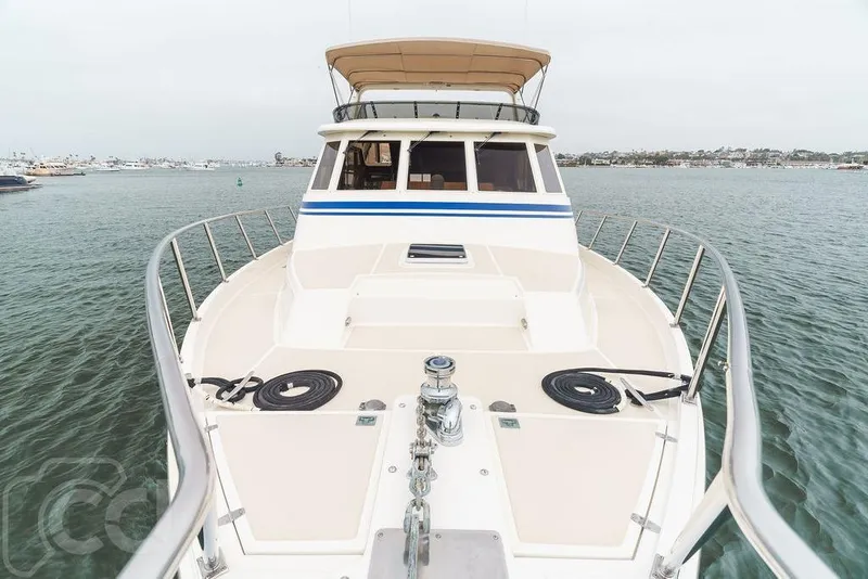 Slide: The Image of 1999 Offshore Yachts 52 Pilothouse on calm waters, showcasing spacious deck and pilothouse. - 2