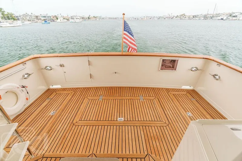 Slide: The Image of 1999 Offshore Yachts 52 Pilothouse deck with wooden flooring and American flag. - 7