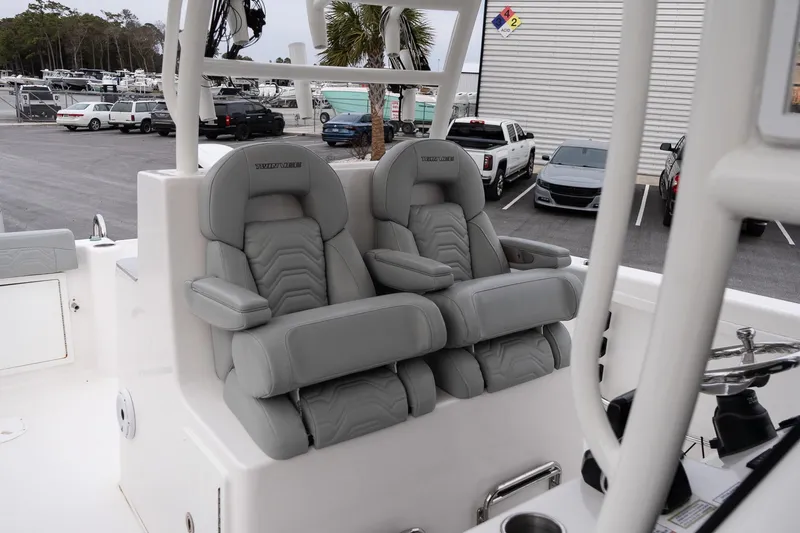 Slide: The Image of 2023 Twin Vee 280 GFX CC boat with luxurious gray seating in a marina setting. - 17