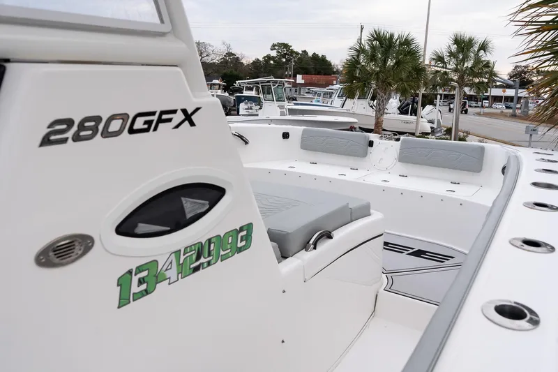 Slide: The Image of 2023 Twin Vee 280 GFX CC boat interior with seating and palm trees in background. - 18