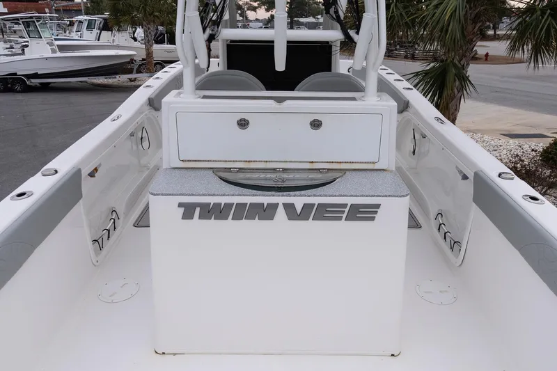 Slide: The Image of 2023 Twin Vee 280 GFX CC boat interior with storage and seating, docked near palm trees. - 7