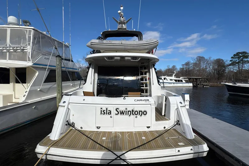 Slide: The Image of 1999 Carver 530 Voyager Pilothouse yacht docked, featuring a spacious deck and sleek design. - 4