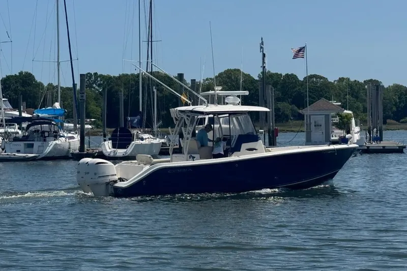 The Image of 2015 Cobia 296 Center Console boat docked in a marina with other vessels. - 0