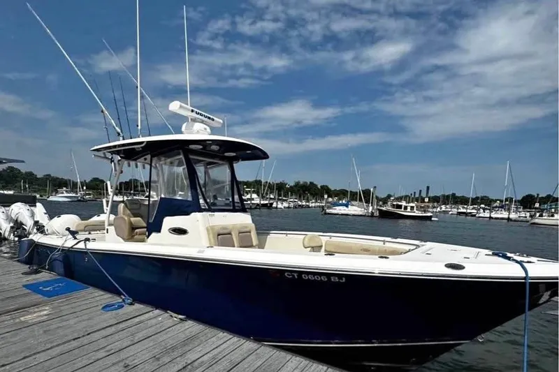 Slide: The Image of 2015 Cobia 296 Center Console boat docked at marina under blue sky. - 1