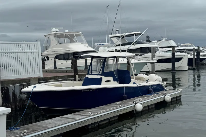 Slide: The Image of 2015 Cobia 296 Center Console boat docked at marina, overcast sky. - 2
